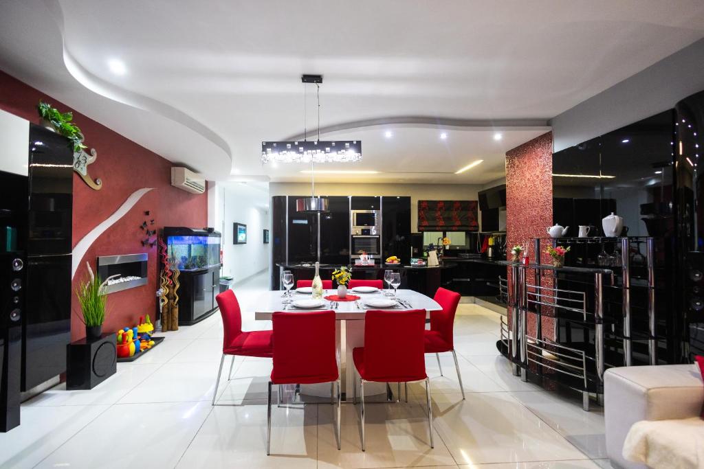 una sala da pranzo con un tavolo e sedie rosse di Modern, stylish & comfortable 3 bedroom apartment with jacuzzi, aquarium and private yard with barbeque a Mellieħa