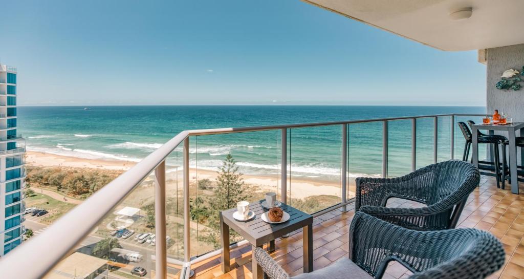 een balkon met 2 stoelen en de oceaan bij Talisman Beachside Broadbeach in Gold Coast