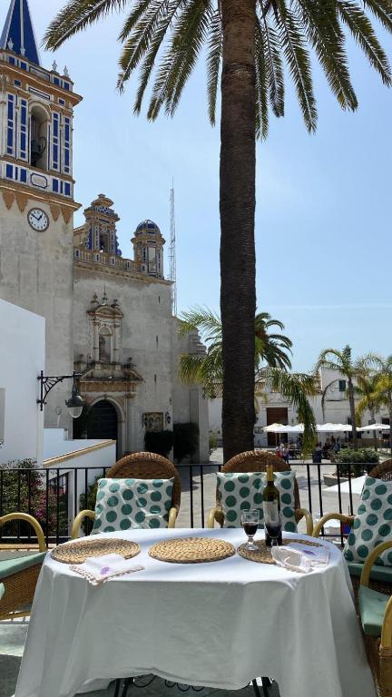 a table with chairs and a clock tower in the background at Casa Michel in Chipiona