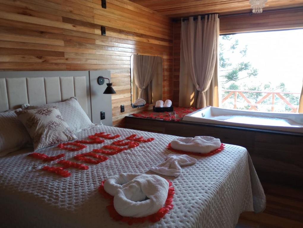a bedroom with a bed with towels and a tub at Cabana Alpen Ville 01 - Rural com Banheira de Hidromassagem in Bom Jardim da Serra