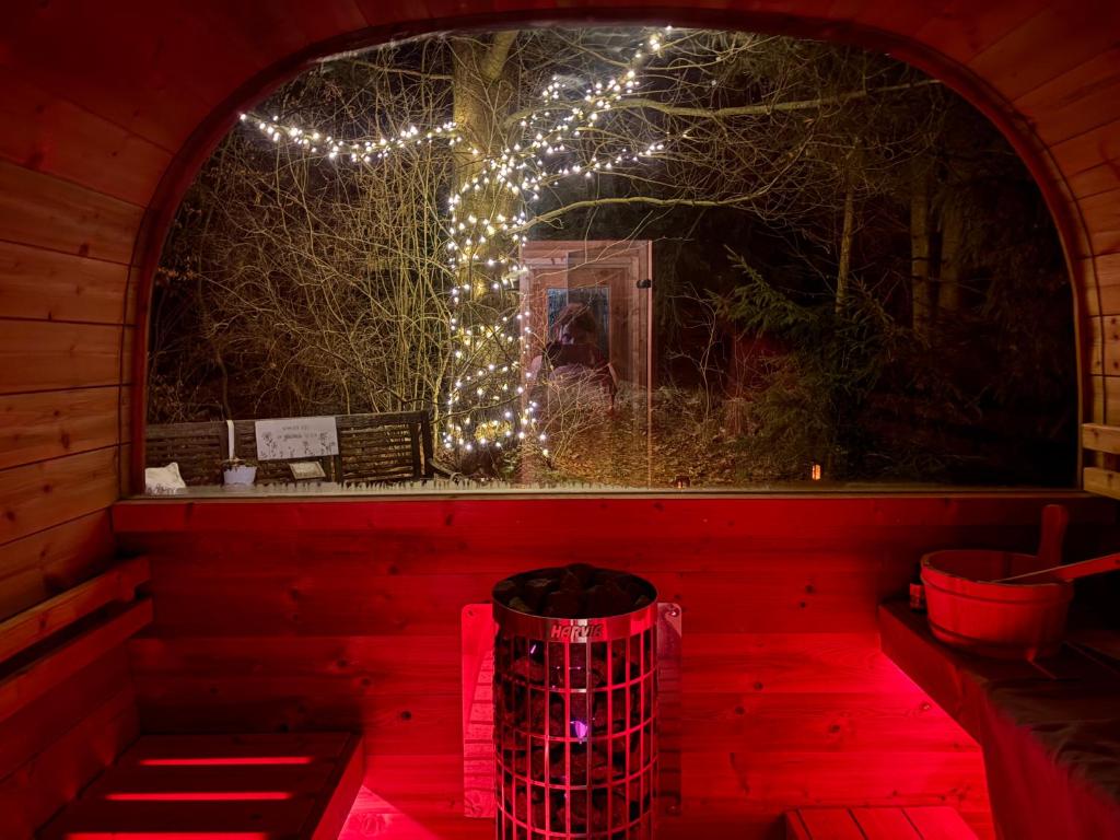 a red room with a tree with lights on it at Frankenwald Ferienhaus FourStars am See in Lichtenberg, Bayern, Oberfranken, Bad Steben - Hof -Saale, Rennsteig in Lichtenberg