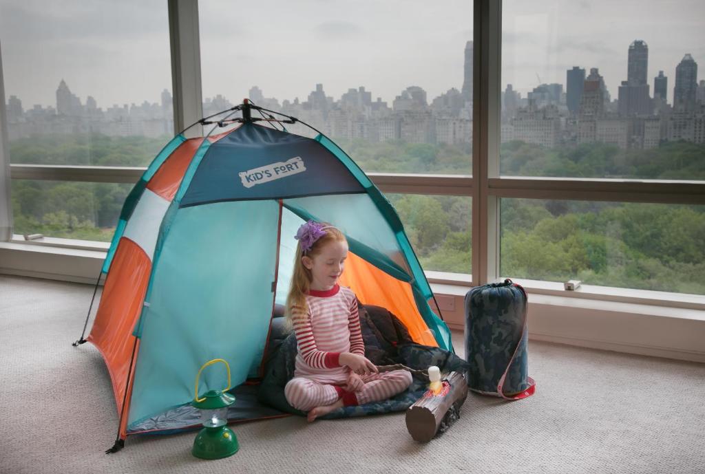 a little girl sitting in a tent in front of a window at Trump International New York in New York