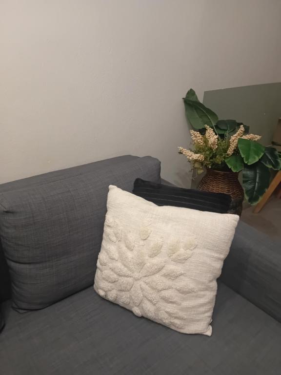 a white pillow sitting on a gray couch with a plant at Christi Iuxury Apartment in Preveza