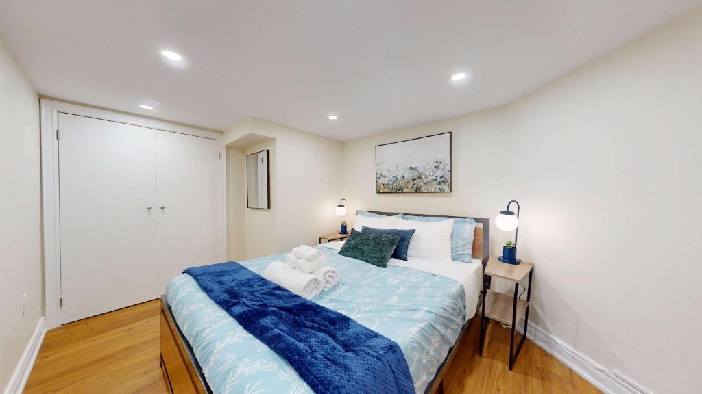 a bedroom with a large bed with a blue blanket at Stylish Basement Suite for 4 Near Cafes & Parks - Bloor Hotel in Toronto