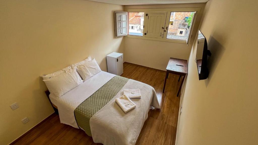 a small bedroom with a bed and a window at Pousada Memórias de Minas in Ouro Preto