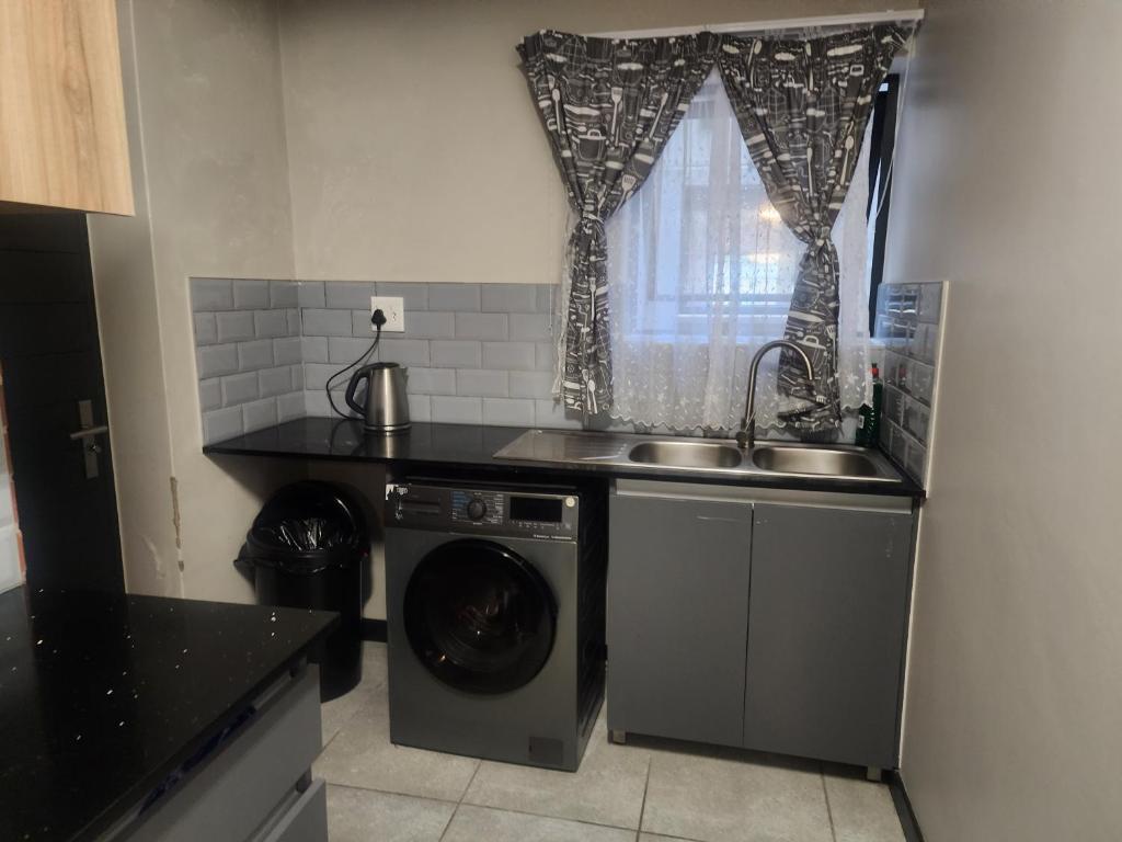 a kitchen with a sink and a washing machine at The white house in Midrand