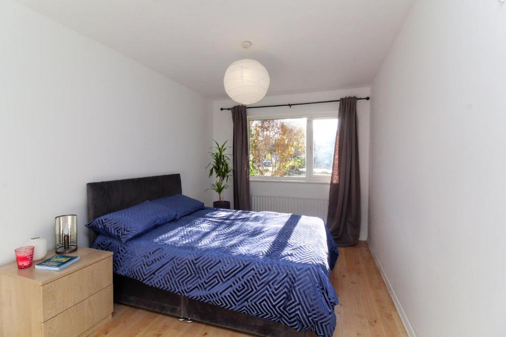 a bedroom with a blue bed and a window at Neat 2 bedroom ground floor flat in Beckenham