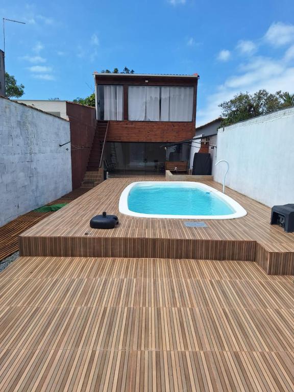 a backyard with a swimming pool and a wooden deck at Casa Boraceia Litoral Norte SP in São Sebastião