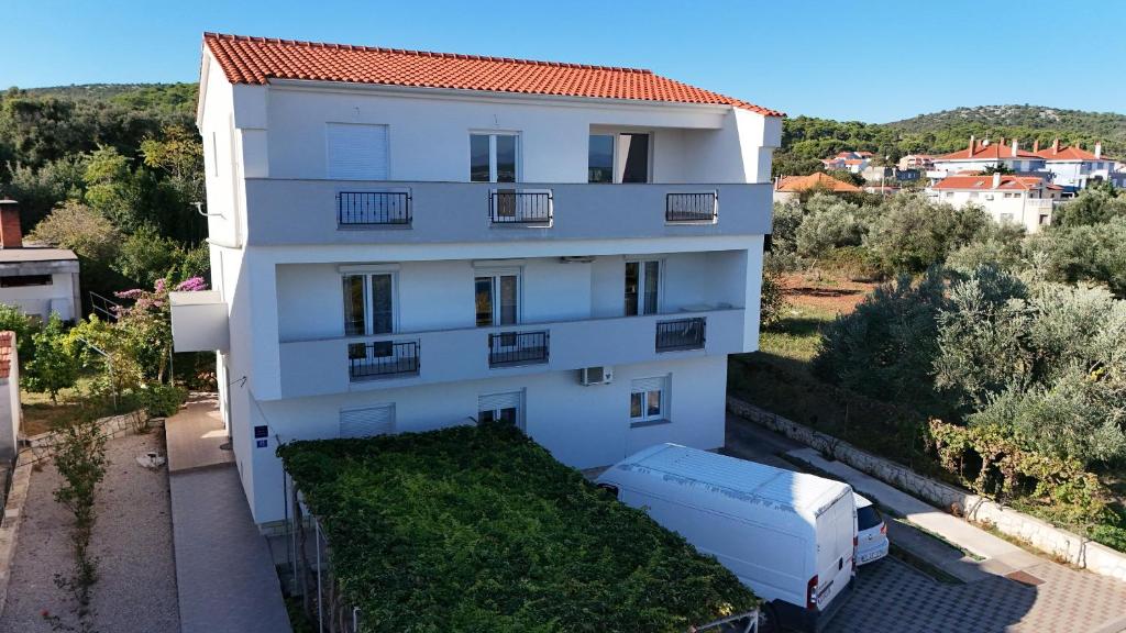 a white building with a truck parked in front of it at Apartments Mirko in Ugrinići