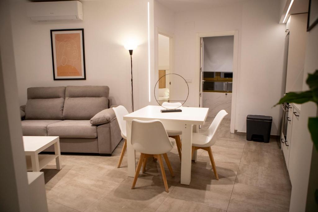 una sala de estar con una mesa, sillas y un sofá en Apartamentos Palma del Río CAROLA, en Linares