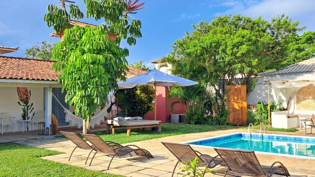 um quintal com piscina e cadeiras e uma casa em Pousada dos Pássaros Geribá em Búzios
