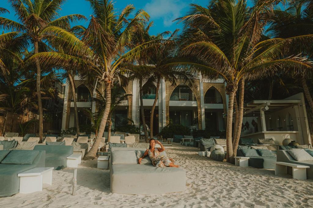a woman sitting on a couch on the beach at Sana Tulum Beachfront Boutique Hotel in Tulum