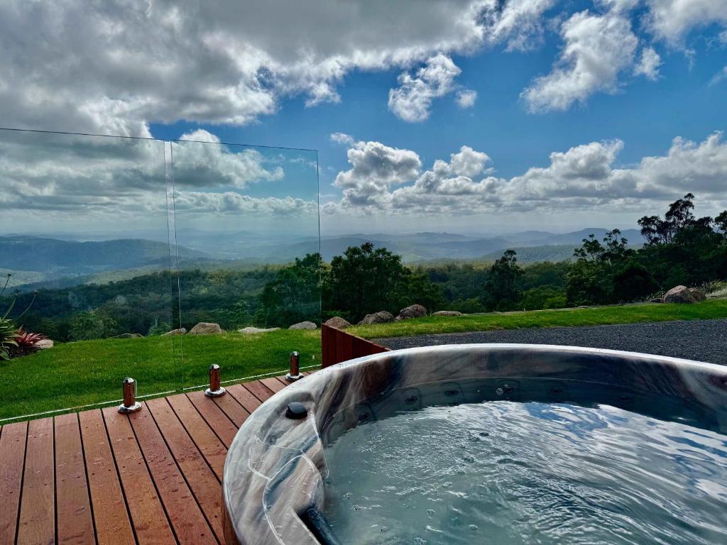 a hot tub on a deck with a view of the mountains at The Quince Cottage - 2 Bedrooms in Ravensbourne