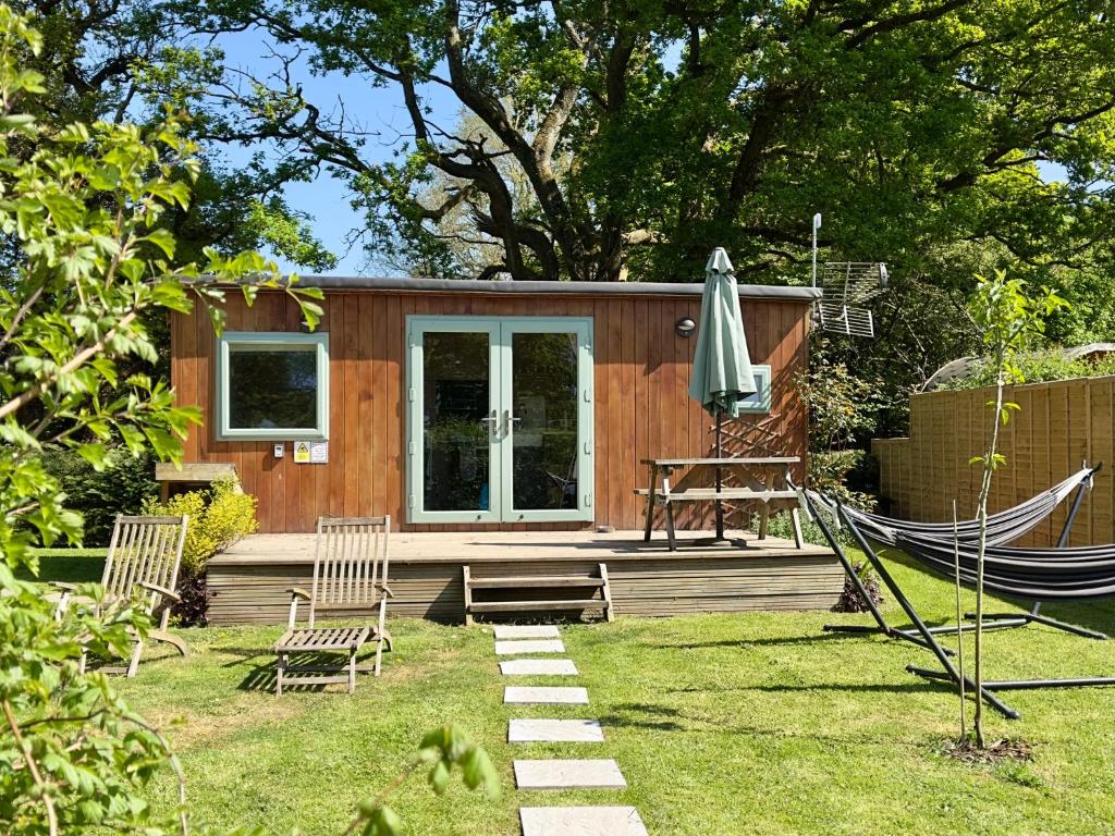 ein winziges Haus mit Hängematte im Hof in der Unterkunft The Hideaway at Hidden Wood Glamping in Corsley