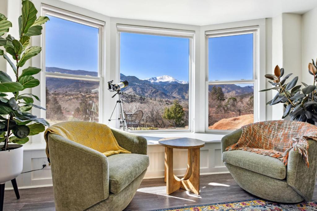 two chairs and a table in a room with windows at Peak View Guesthouse - Walk to Garden of the Gods - Hot Tub - Epic Views! in Colorado Springs