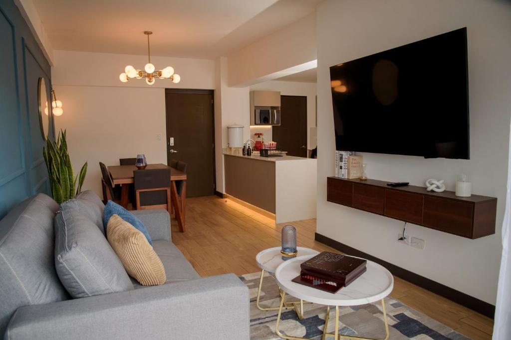 a living room with a couch and a large tv at Glam - Apartamento exclusivo cerca del Consulado de México y centros comerciales in Quetzaltenango
