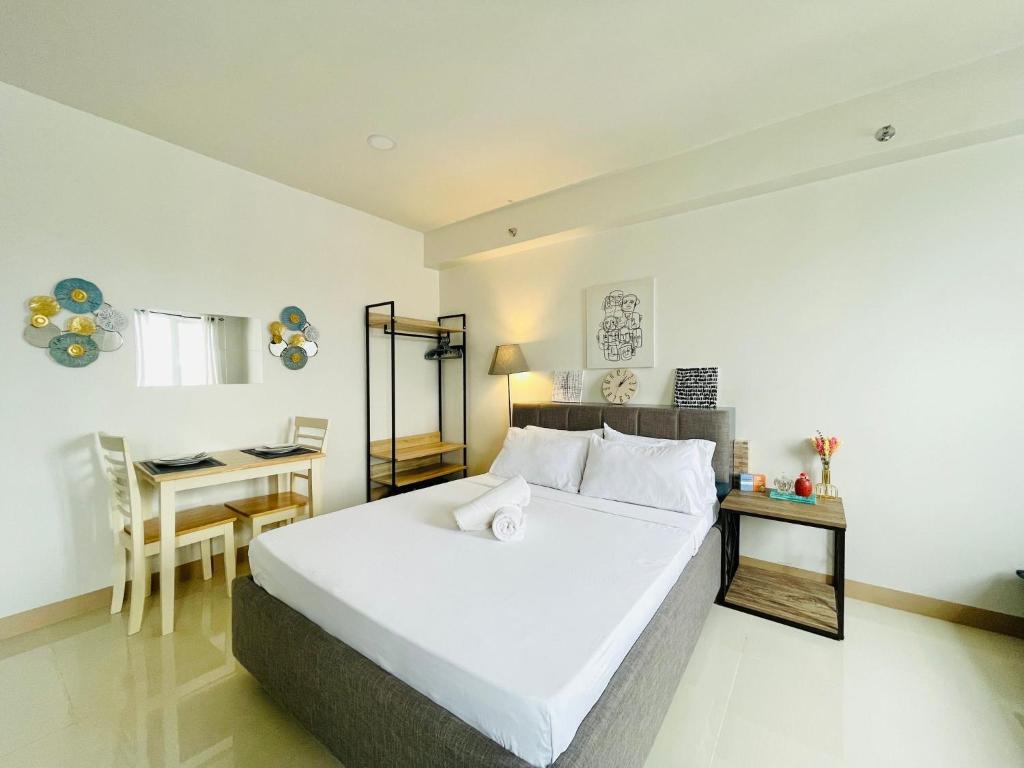 a bedroom with a large white bed and a table at Elegant Style Studio in SMDC in Cari Mayor