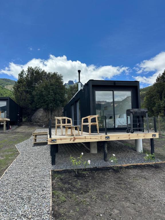 una pequeña casa negra sentada en una plataforma de madera en Nina apart Meliquina, en San Martín de los Andes