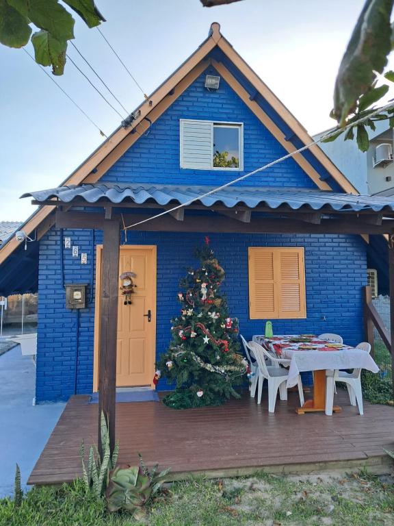 a blue house with a christmas tree on a deck at Chalé aconchegante à 300mts do mar in Arroio do Silva