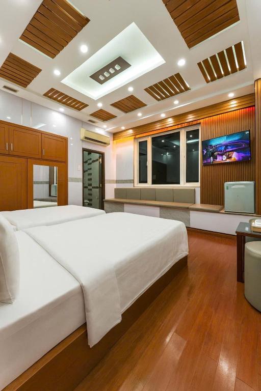 a bedroom with a large white bed and a flat screen tv at Van Ha Hotel Etown - Nhà Ga T3 Sân Bay TSN in Ho Chi Minh City