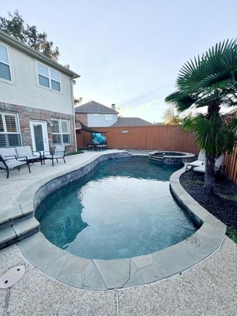 a swimming pool in a yard next to a house at Spacious Centrally Located with Heated Pool in Frisco