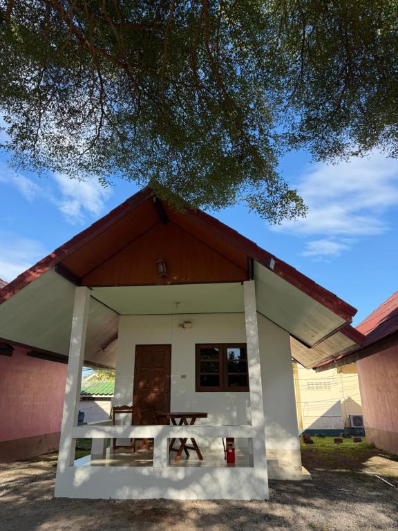 een klein huis met een picknicktafel ervoor bij ปลาตอง รีสอร์ท in Chao Lao Beach