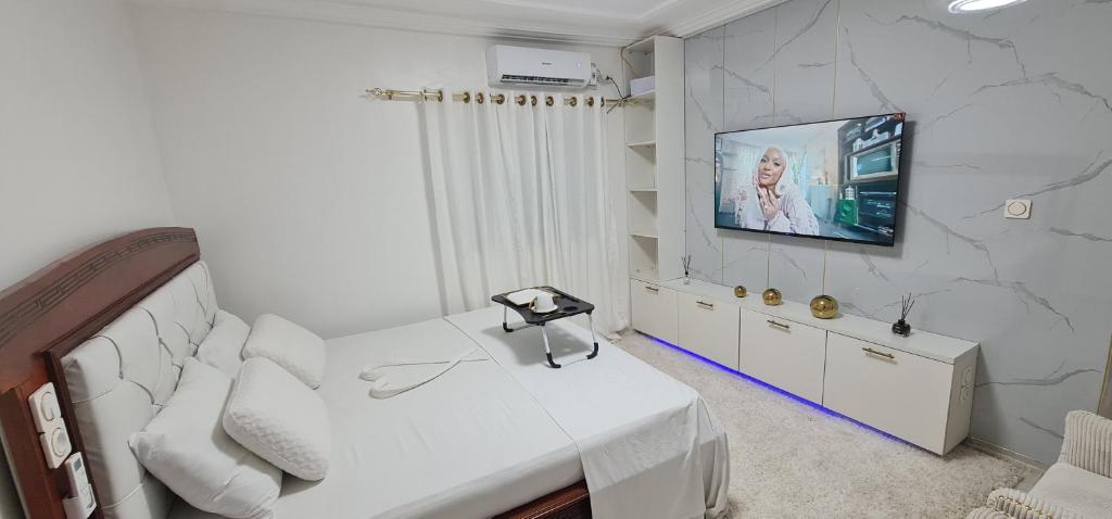 ein Schlafzimmer mit einem Bett und einem Fernseher an der Wand in der Unterkunft O'sena in Cotonou