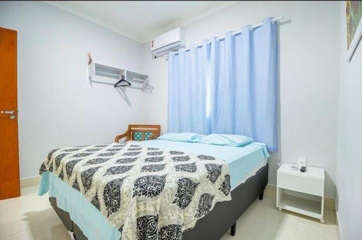 a bedroom with a bed with a black and white blanket at K&S Kanto Sereno in Pirenópolis