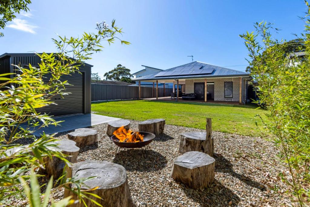 a backyard with a fire pit and logs at Catch & Relax - Pet Friendly - 4 Mins Walk to Beach in Callala Beach