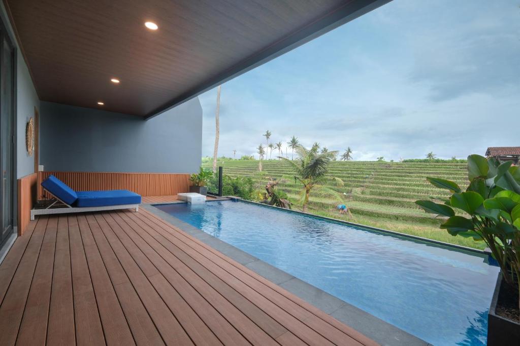 Bellevue Villa Canggu في Pererenan: منزل به مسبح وسطح خشبي