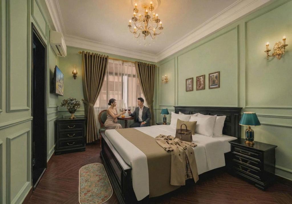 1 dormitorio con 1 cama y 2 personas sentadas en una mesa en Vina Vintage Hotel, en Hue