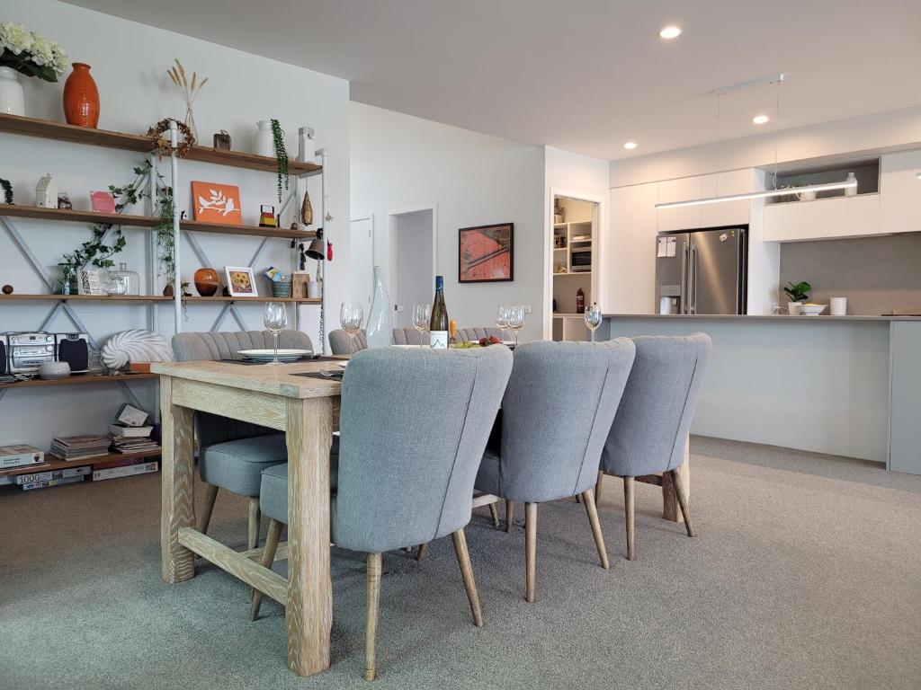 a dining room with a wooden table and blue chairs at Hosts on the Coast Skippers Landing in Whitianga