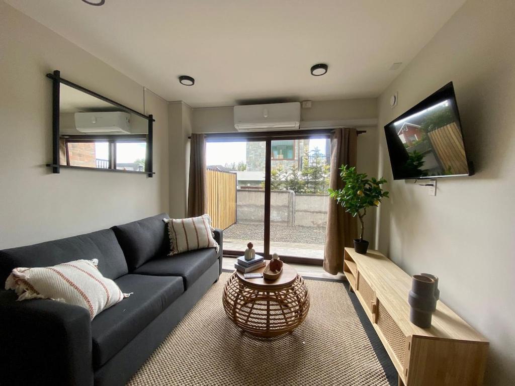 a living room with a blue couch and a tv at Wifi, Parking, AC, Bien equipado, 5 min del centro y todo cerca in Osorno