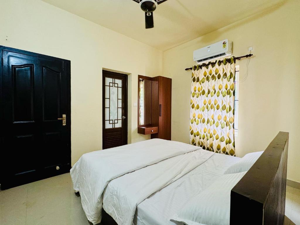 a bedroom with a bed and a black door at Anandha Vibes in Guruvāyūr