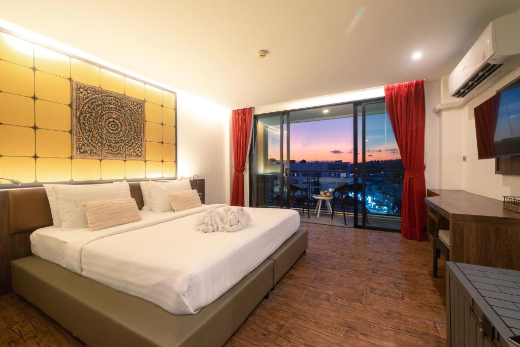 The Beach Residence Kata في شاطئ كاتا: غرفة نوم بها سرير ونافذة كبيرة