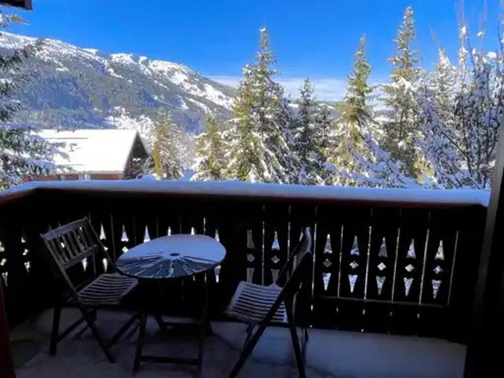 a table and chairs on a balcony with a snow covered mountain at Appartement à Méribel 4 pers, piscine, skis aux pieds - FR-1-411-1007 in Chandon