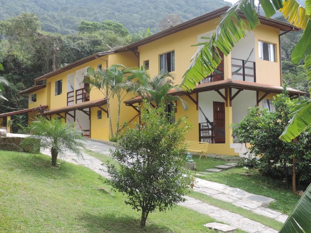 una casa amarilla con árboles delante de ella en Pousada Portal das Estrelas, en Trindade
