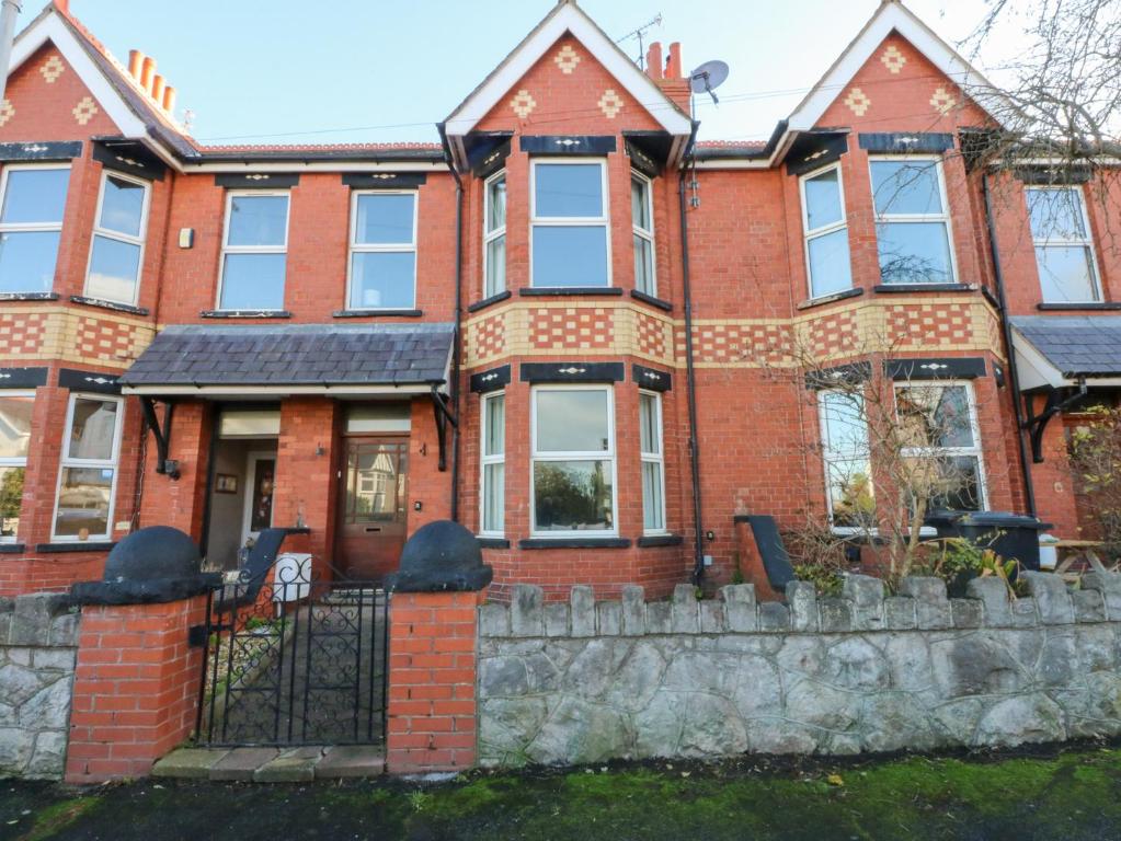 a red brick house with a stone fence at Canning Lodge in Colwyn Bay
