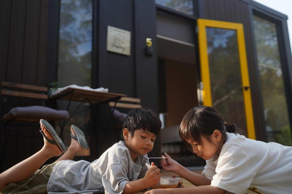 Konggu Valley Retreat Hut X By Tiny Away في T'ou-kou: طفلان صغيران يجلسان على الأرض يدخنان