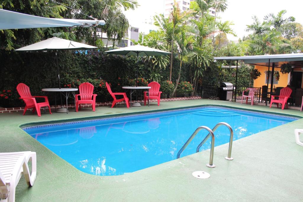 a swimming pool with red chairs and a table and chairs at Hostal Cocos Inn in Panama City