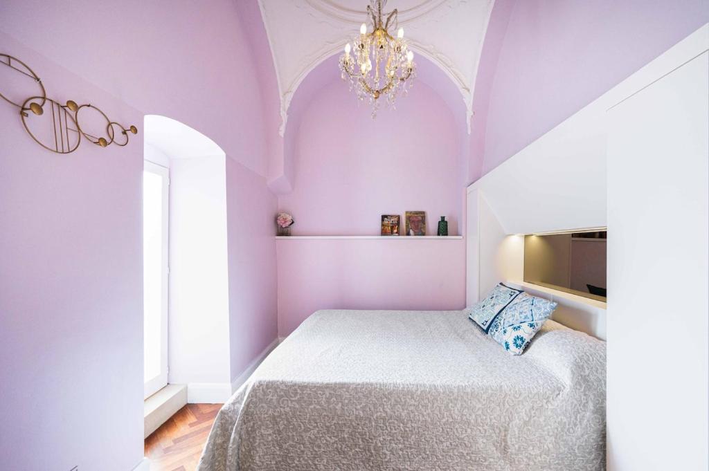 - une chambre avec un lit aux murs violets et un lustre dans l'établissement Palazzino San Francesco, à Catane