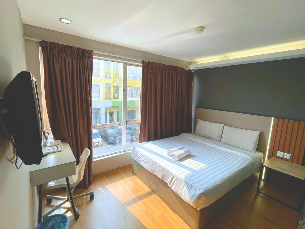 Un dormitorio con una cama y un escritorio y una ventana. en Hotel 99 Bandar Klang (Meru), en Klang