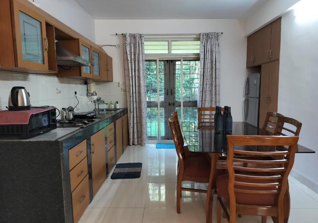 Villa Neesham Grande في بيناوليم: مطبخ مع خزائن خشبية وطاولة وكراسي