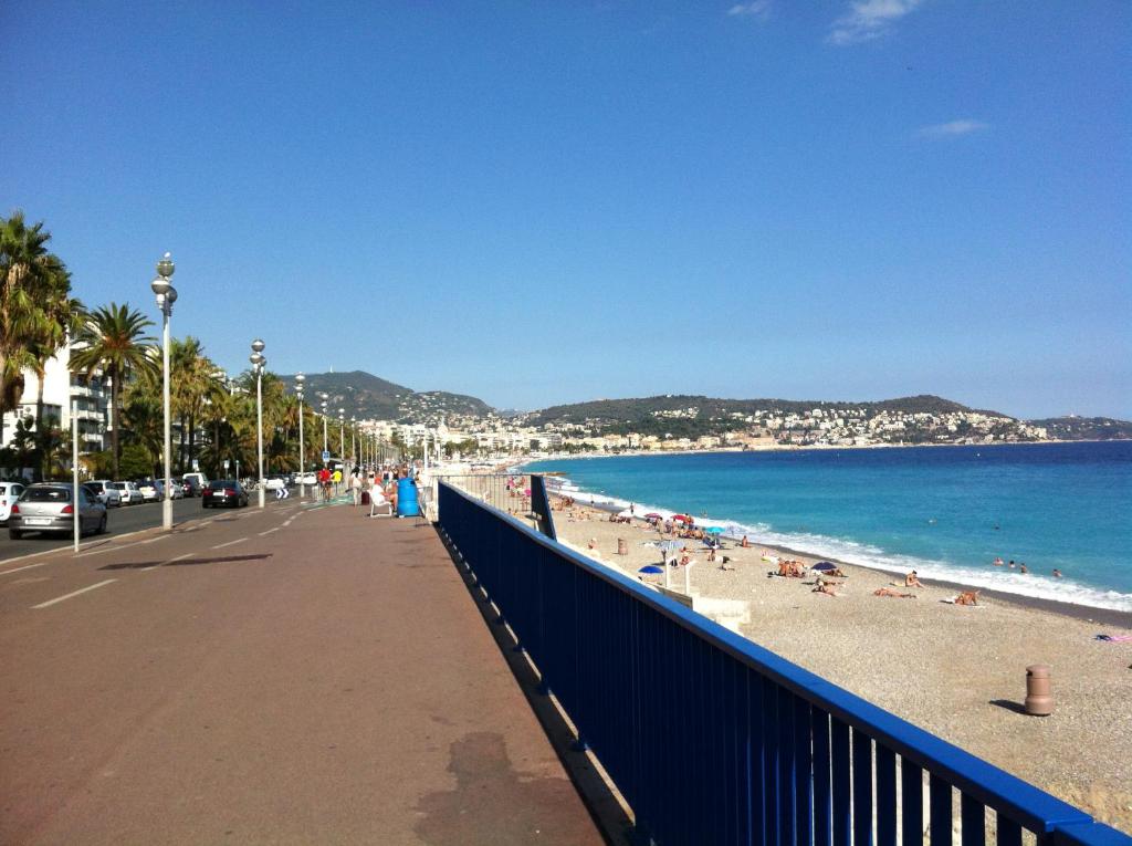 une plage avec une clôture bleue et des personnes sur la plage dans l'établissement Appartement Palais des Dômes avec piscine, à Nice