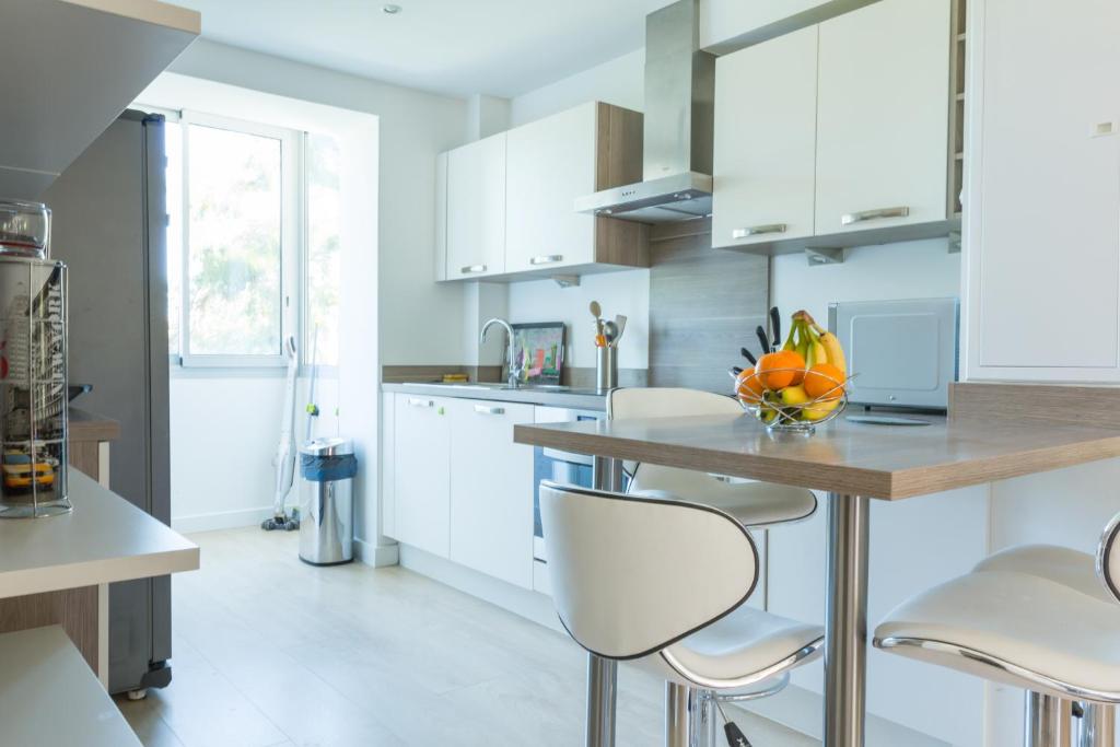 a kitchen with white cabinets and a counter with stools at Résidence La Source in Toulon