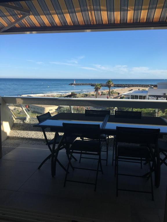 une table et des chaises sur un balcon avec vue sur l'océan dans l'établissement Elixxir, au Cap d'Agde