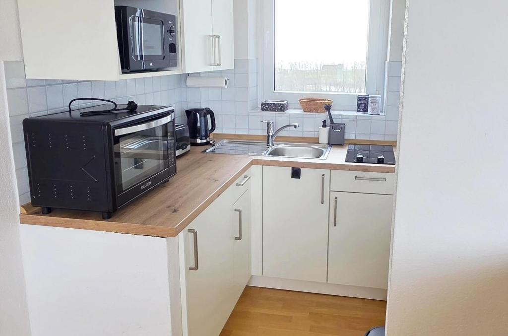 a small kitchen with a microwave and a sink at Tief 10 Austernfischer 708 in Wangerland