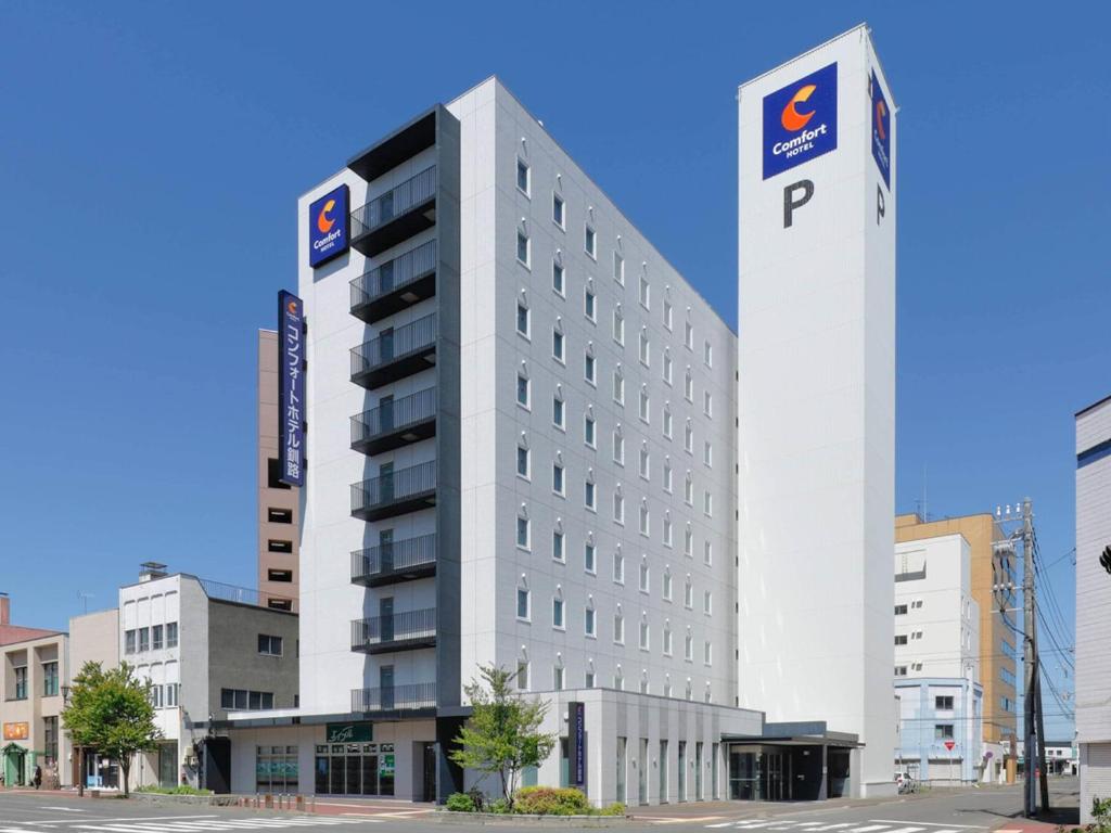 ein hohes weißes Gebäude mit einem AP-Schild darauf in der Unterkunft Comfort Hotel Kushiro in Kushiro