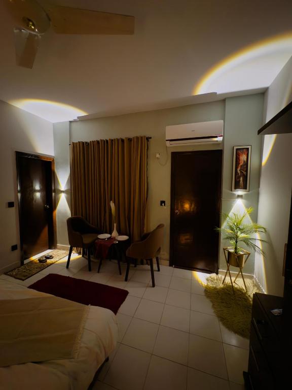 a hotel room with a bed and a table and chairs at Rosewood Cottage in Karachi