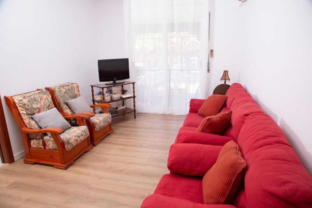 a living room with a red couch and two chairs at GranVia Fira Apartment in Hospitalet de Llobregat